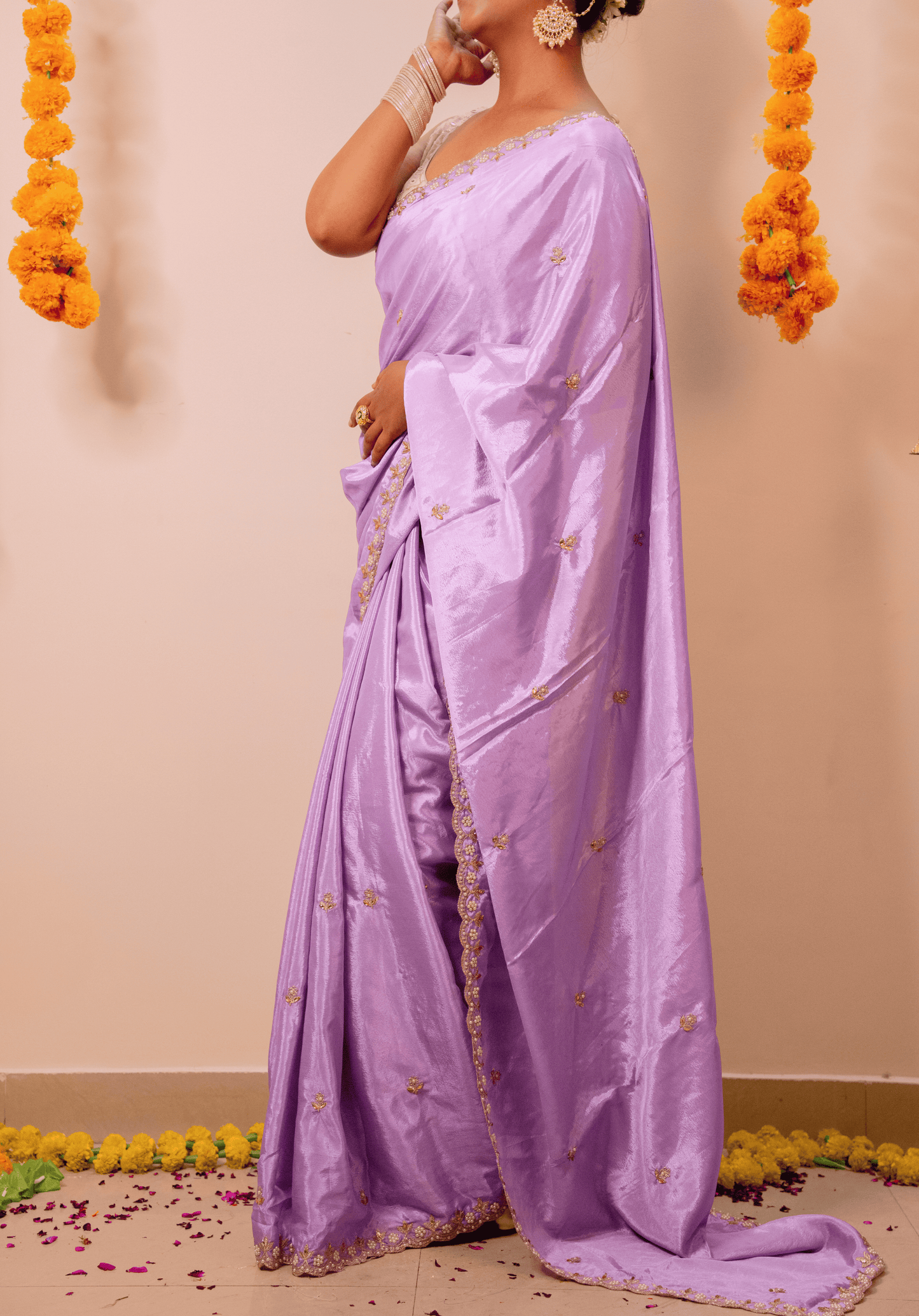 Woman wearing a lilac chinon saree with a beige background and floral decorations.