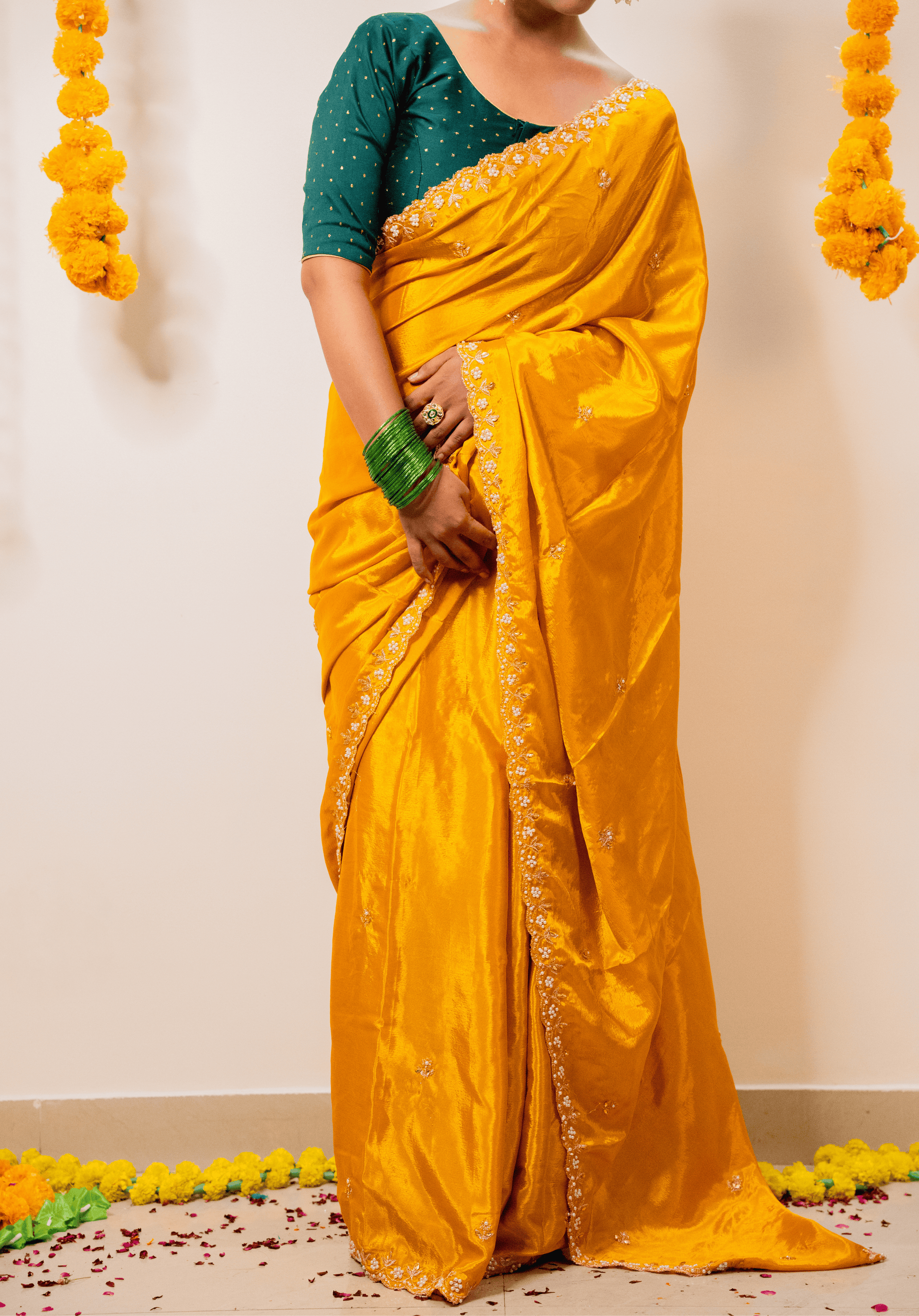 Woman wearing a yellow chinon saree with a green blouse against a plain background