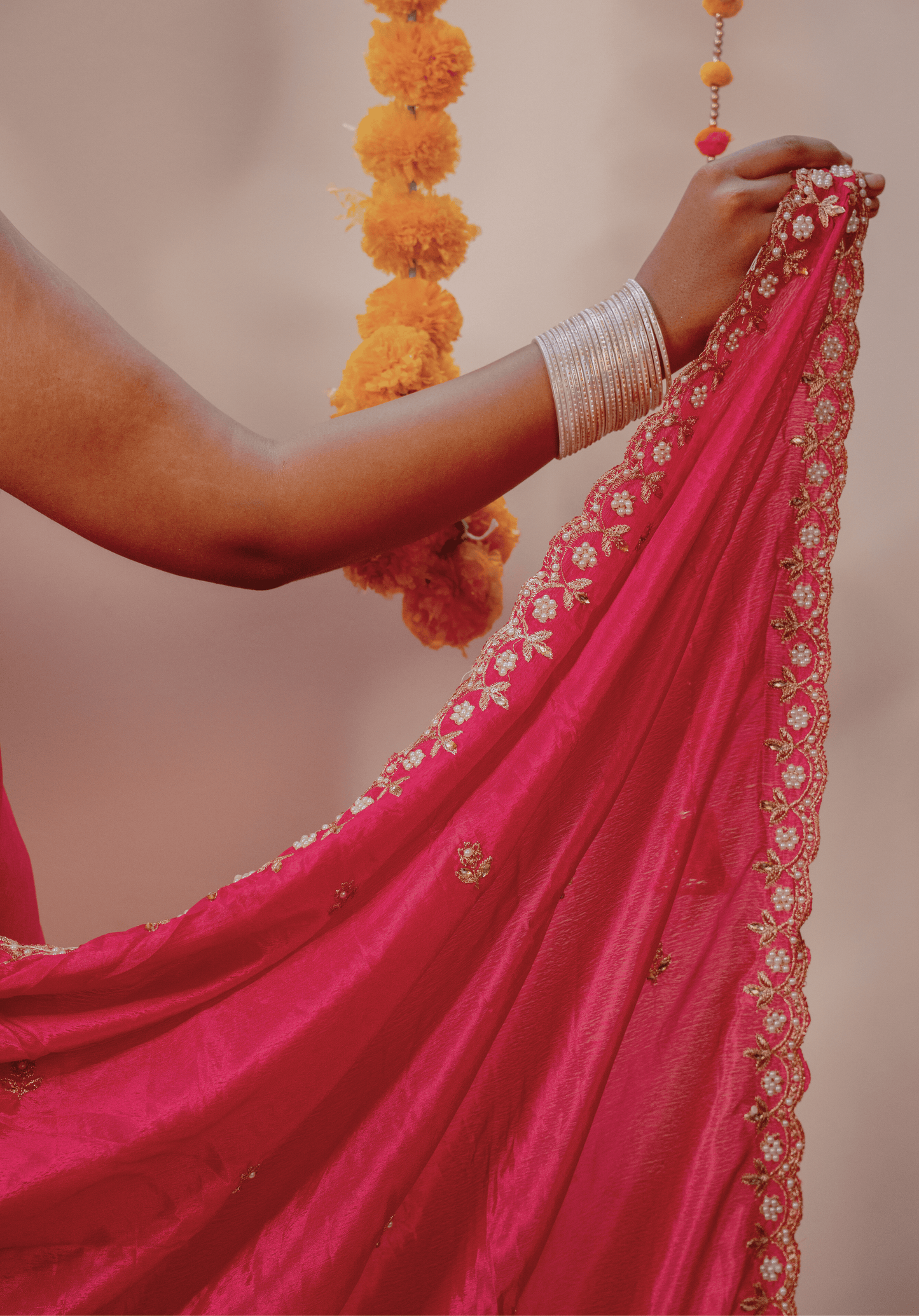 Close-up of a white and gold embroidered border on a pink chinon saree 