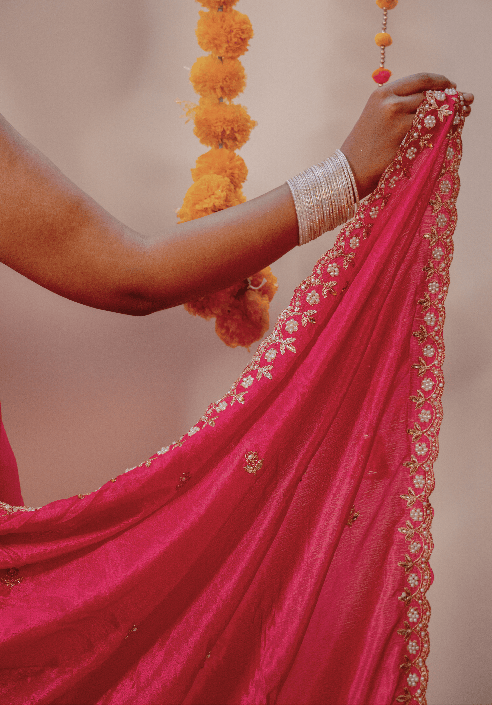 Close-up of a white and gold embroidered border on a pink chinon saree 