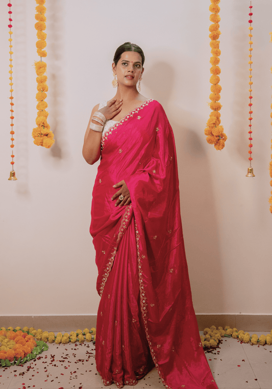 Woman in a bright pink chinon saree with a white and gold embroidered border.