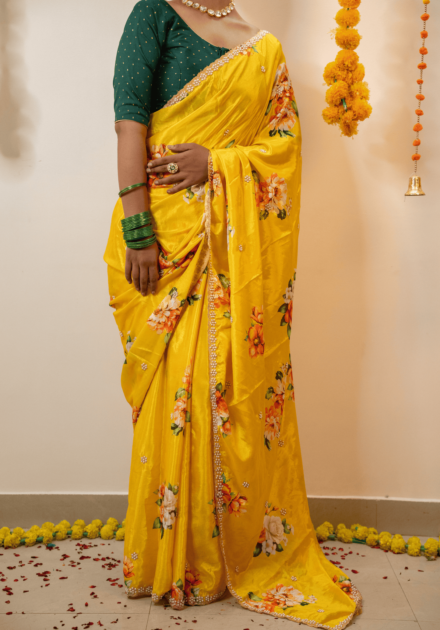 Woman wearing a lemon yellow saree with floral patterns and embroidered border.