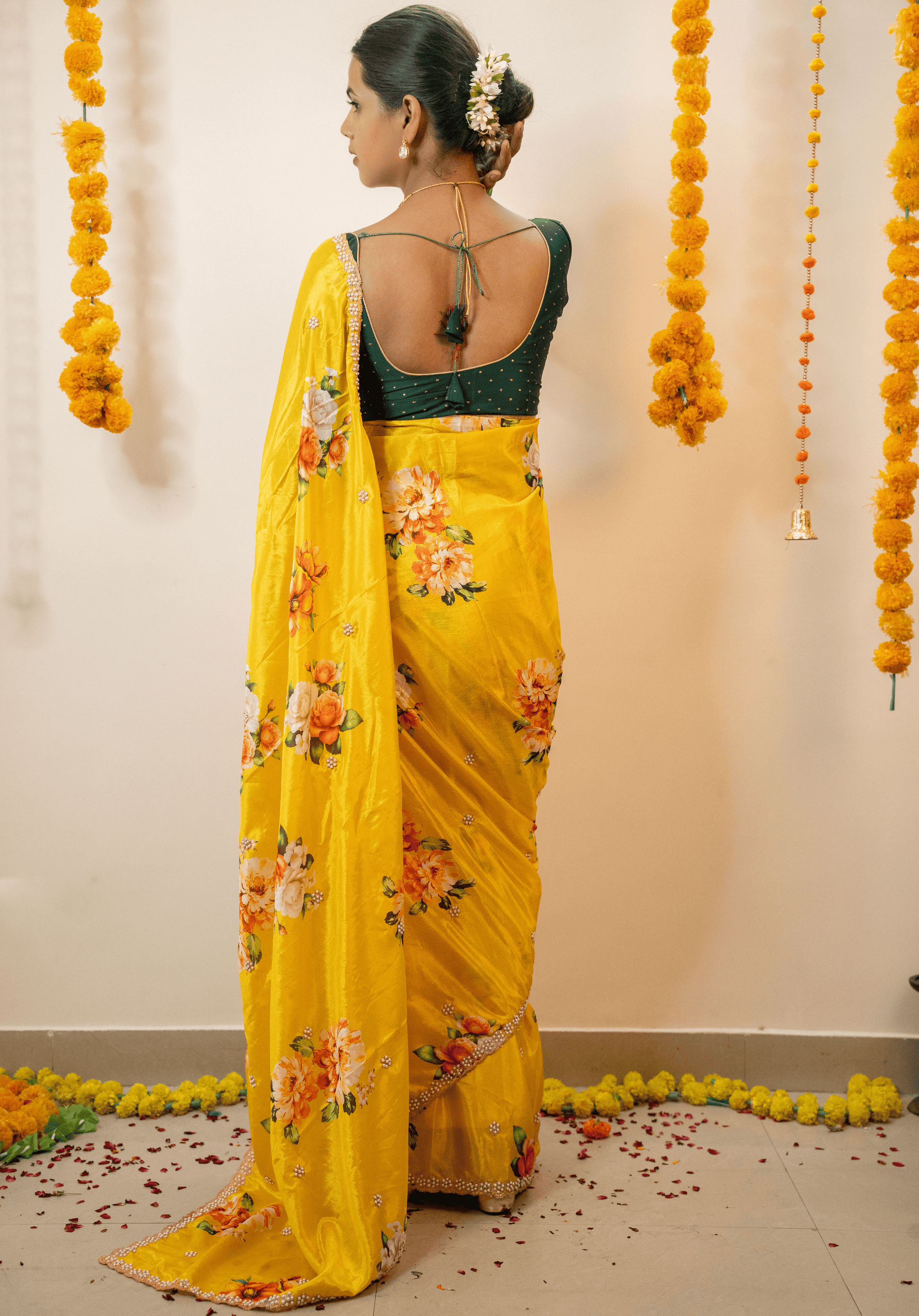 Woman wearing a lemon yellow chinon saree with floral patterns in a decorated indoor setting.
