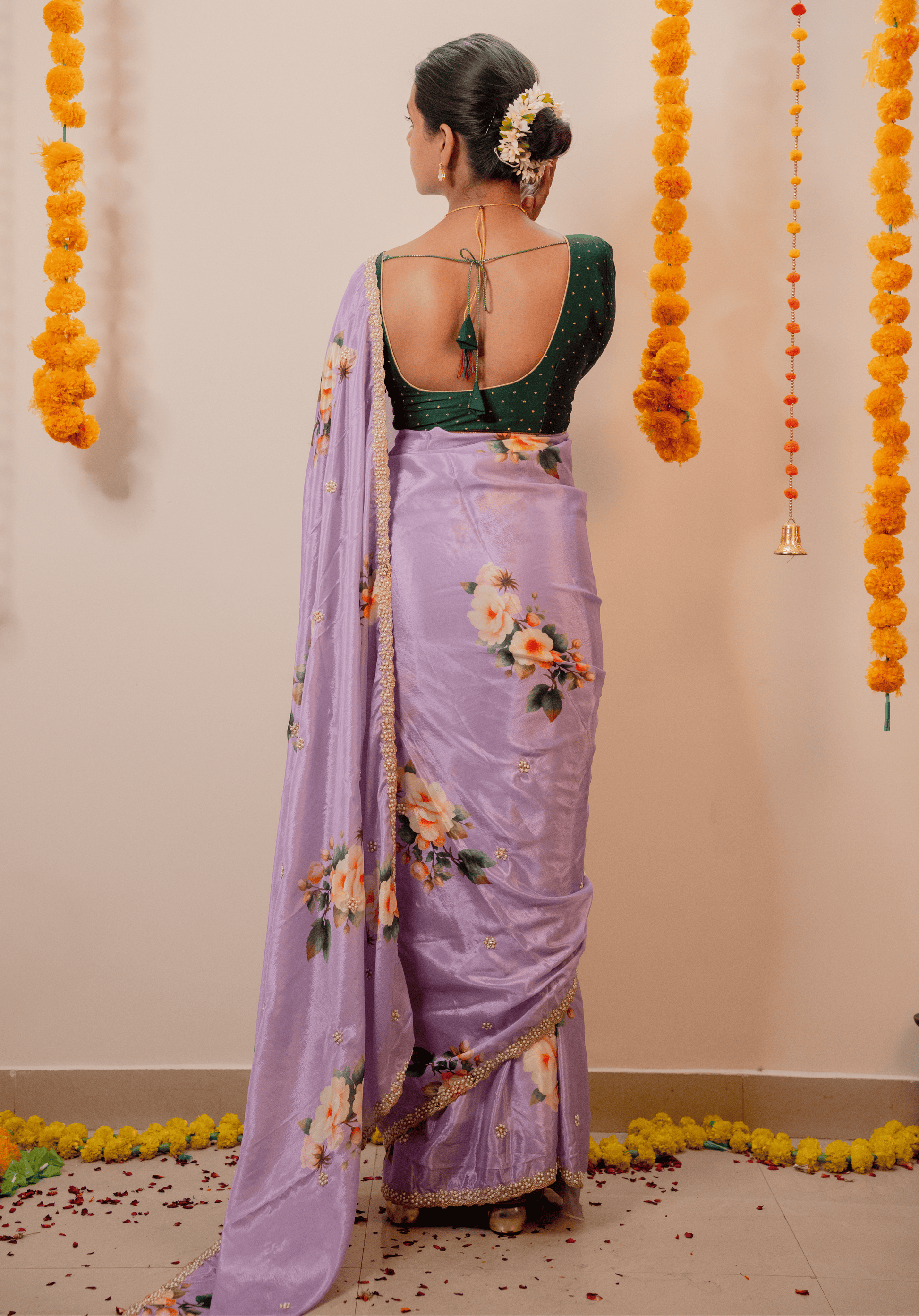 Woman in a lilac chinon saree with floral patterns and embroidered border.