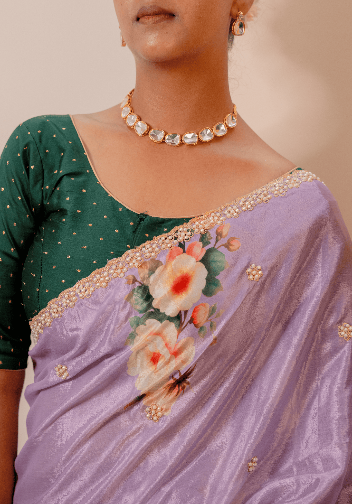 Woman wearing a floral lilac chinon saree and gold jewelry.