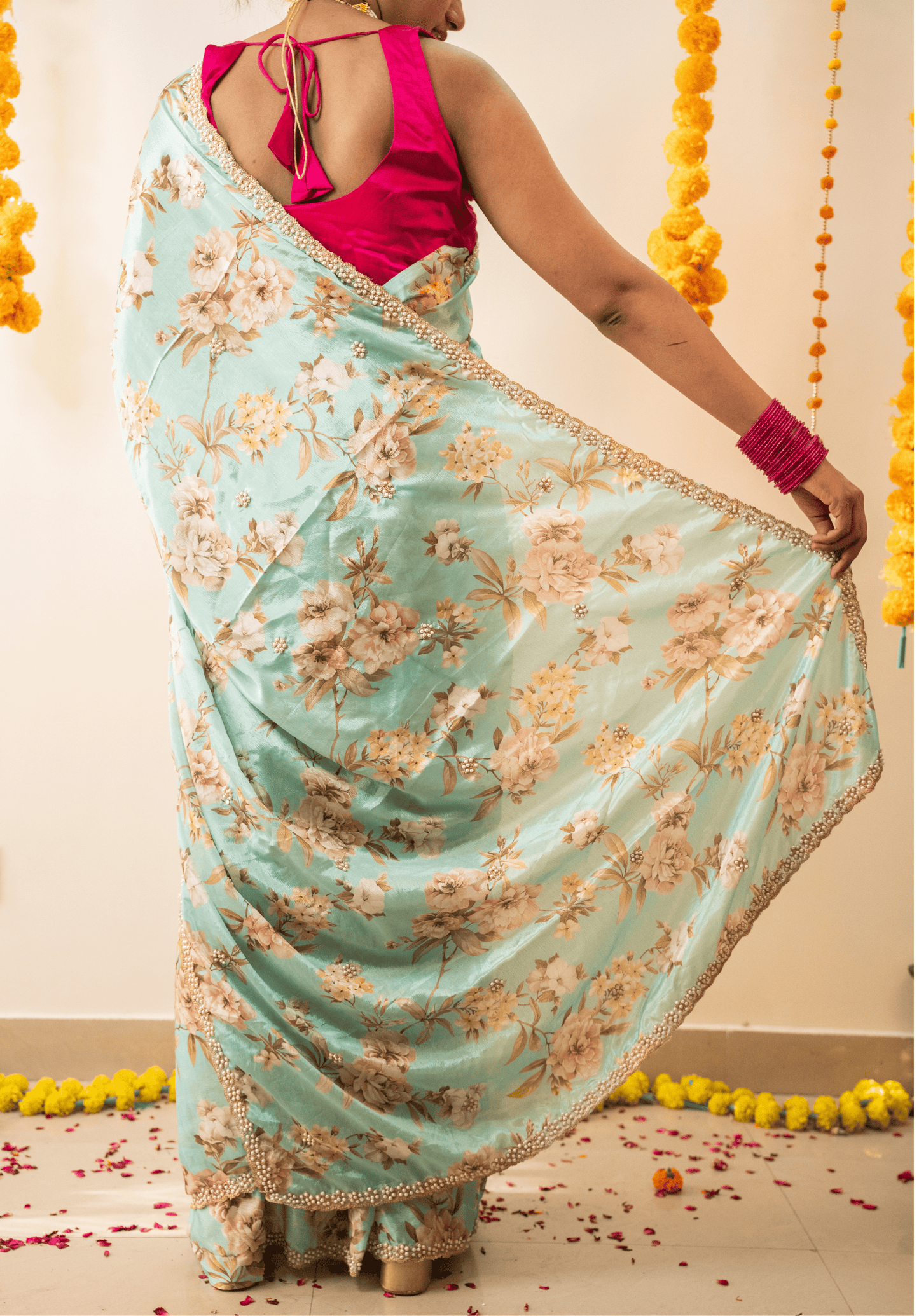 Person wearing a pastel green floral saree with a pink blouse.