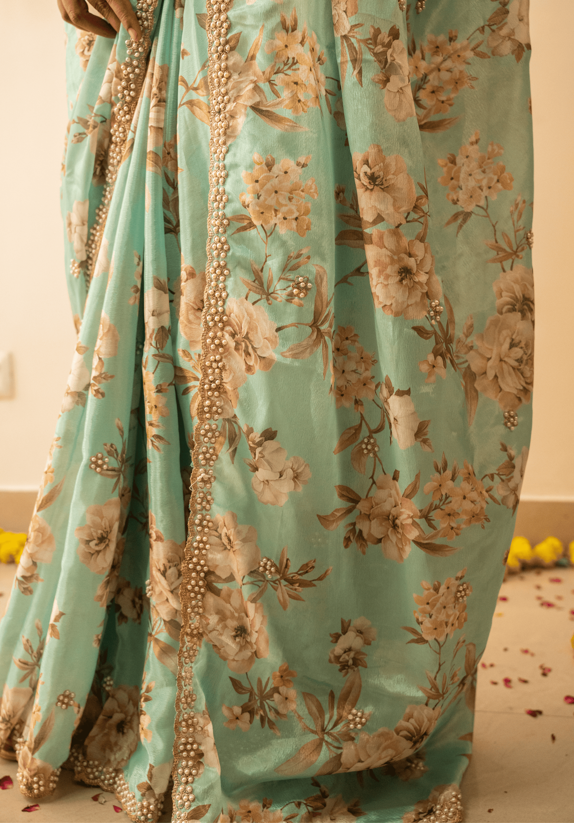 Close up of gold and white embroidered border on pastel green chinon floral saree