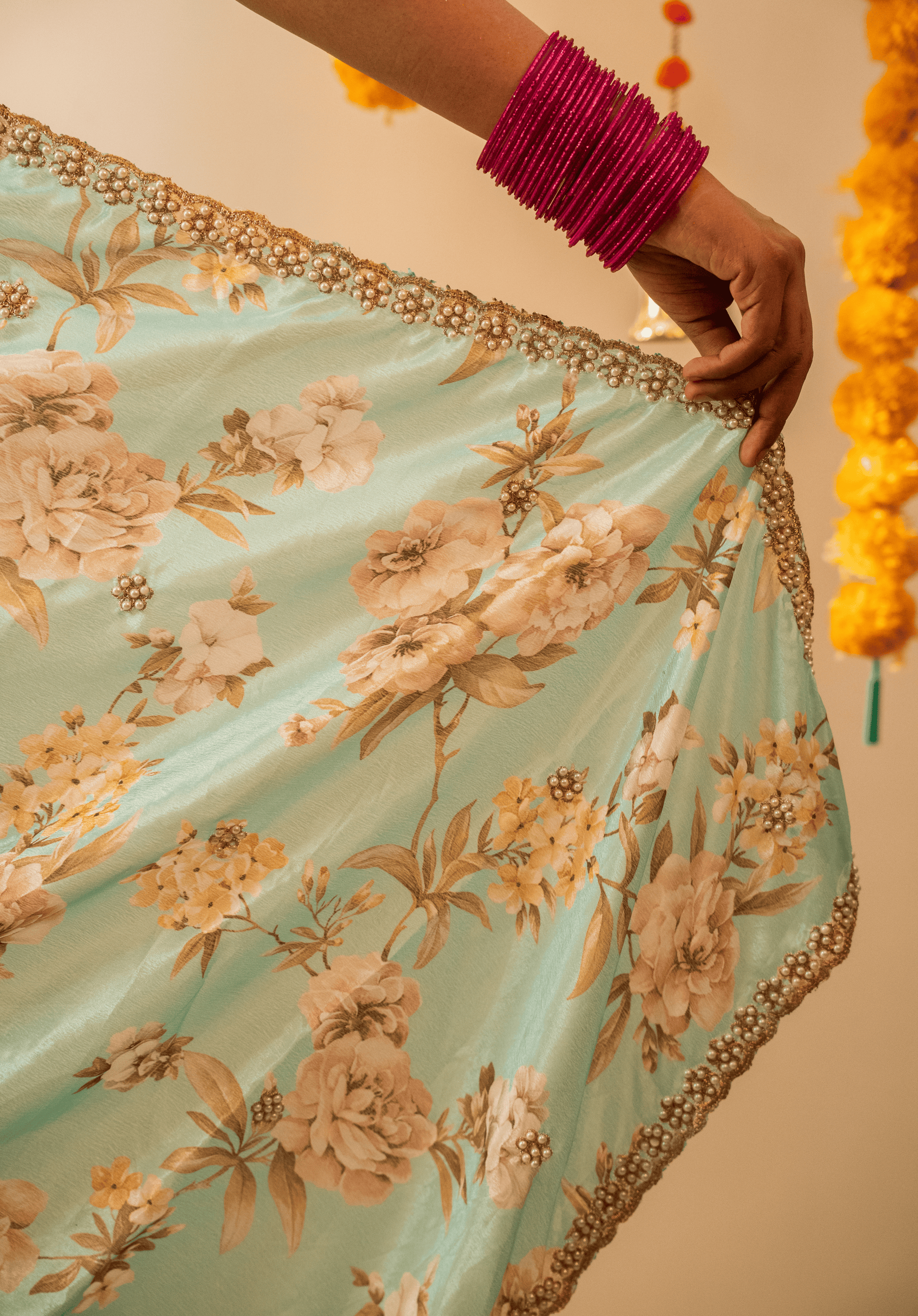 Close up of pastel green chinon floral saree pallu with white and gold embroidery. 