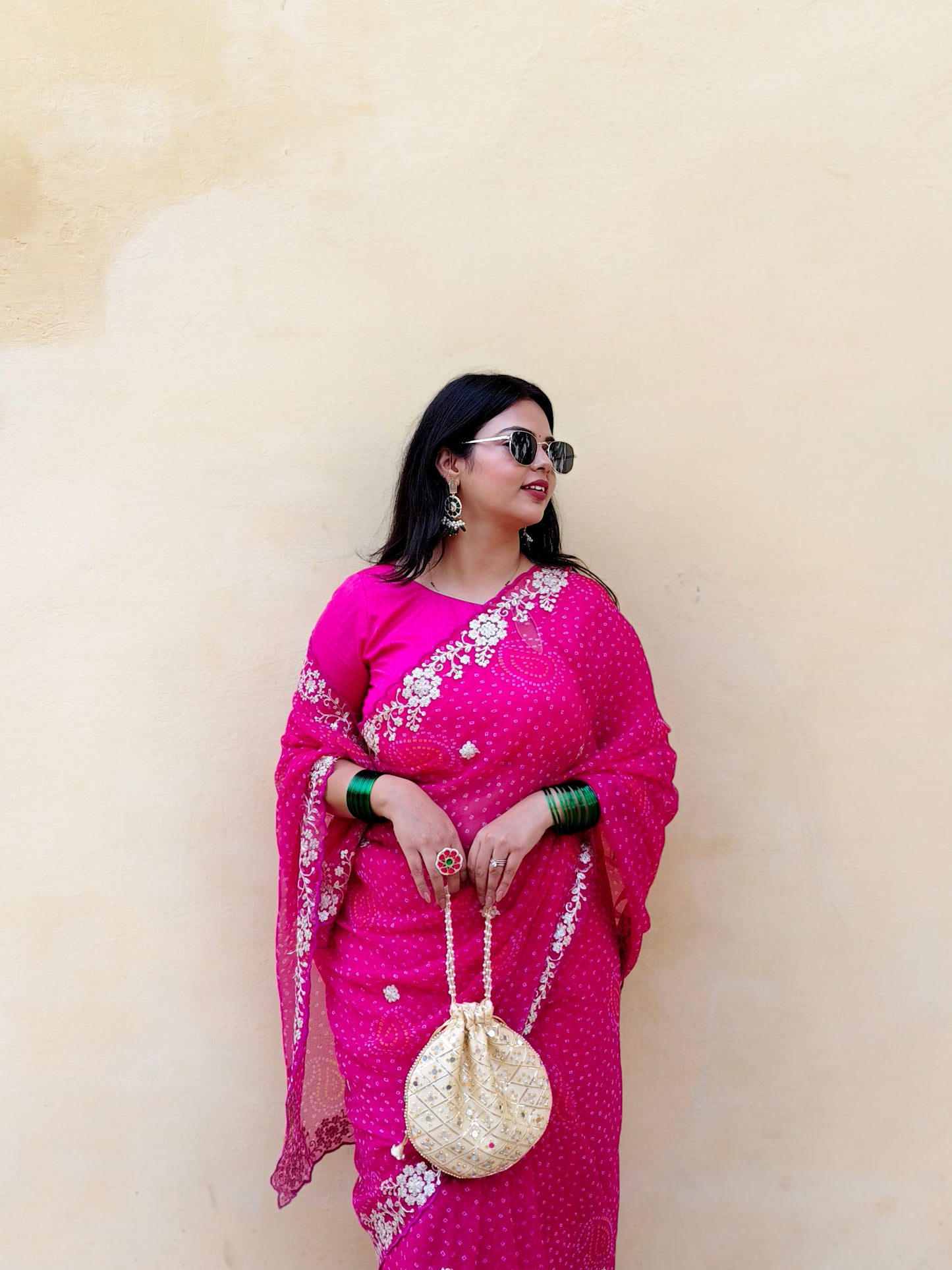 Woman in a bright pink chiffon bandhani saree.