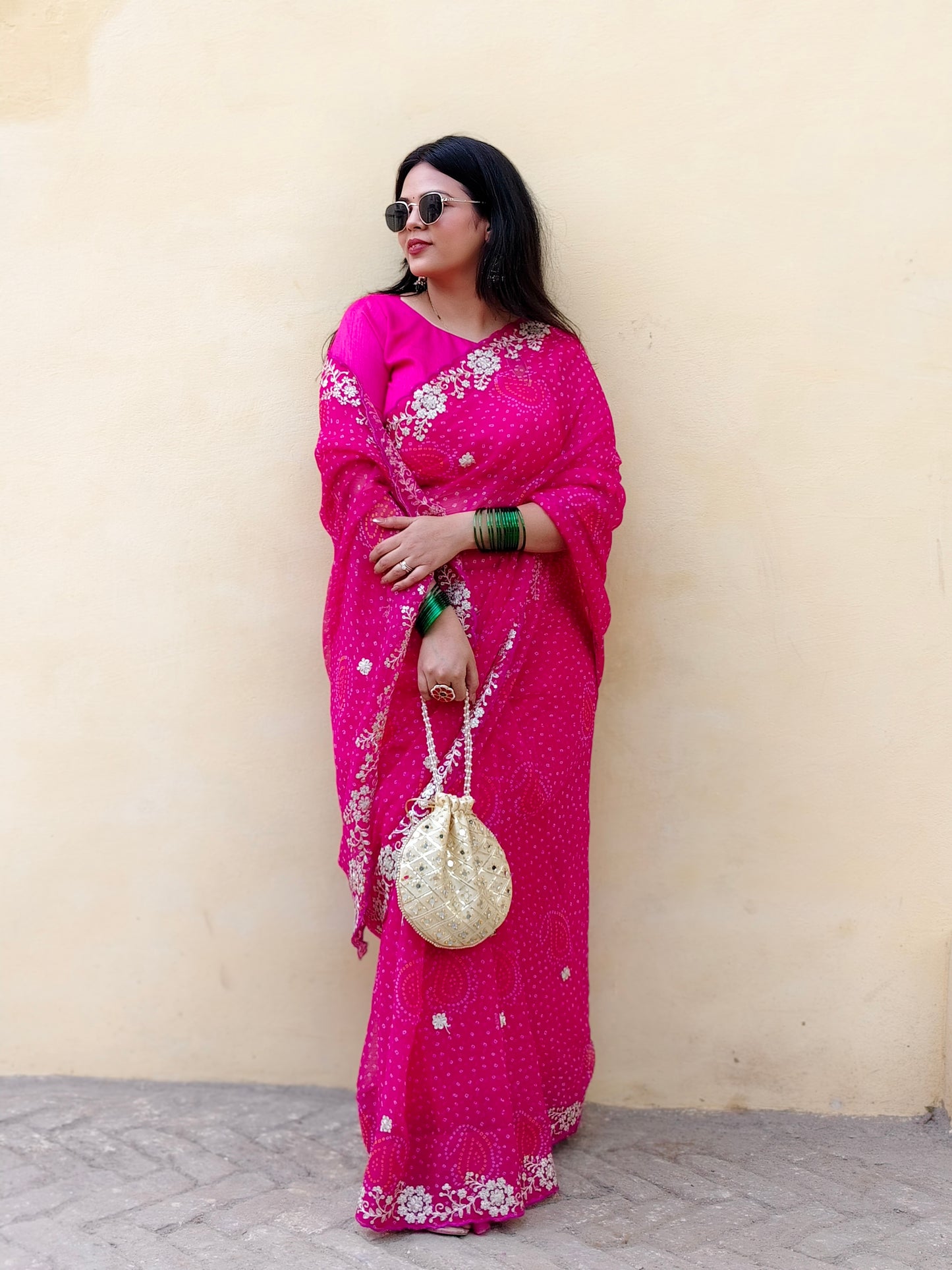 Woman in a bright pink chiffon bandhani saree 