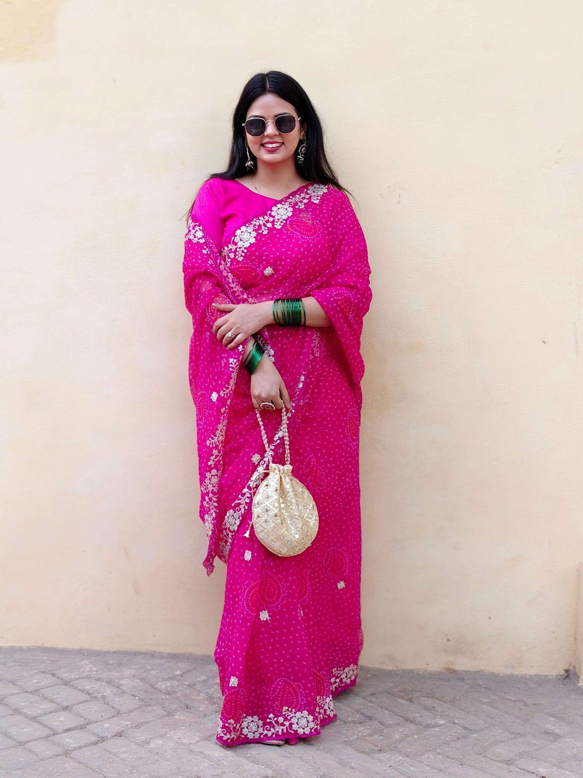 Woman wearing a bright pink pure chiffon bandhani saree for festivities.