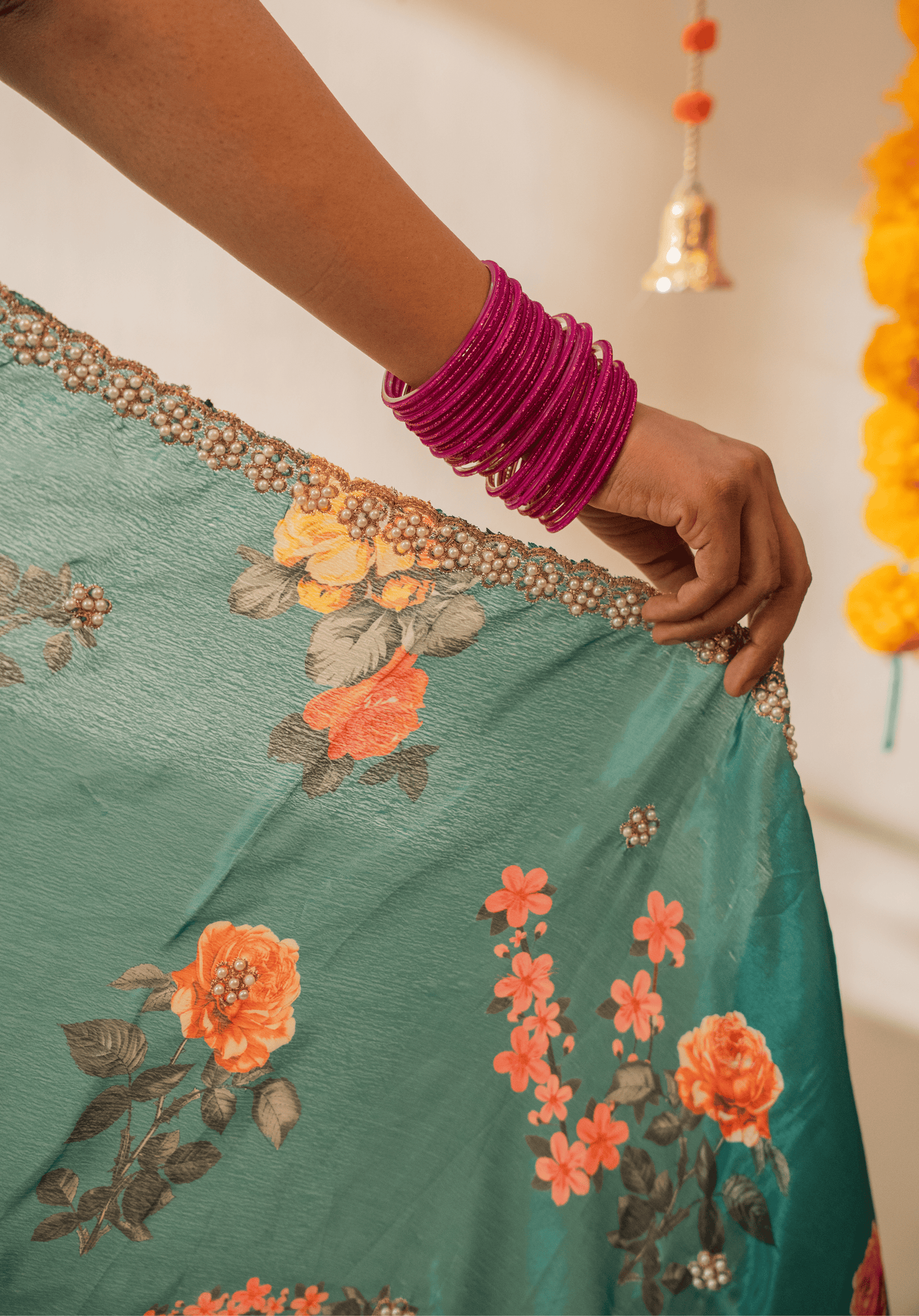 Close up of the gold and white embroidered border on teal green floral chinon saree.